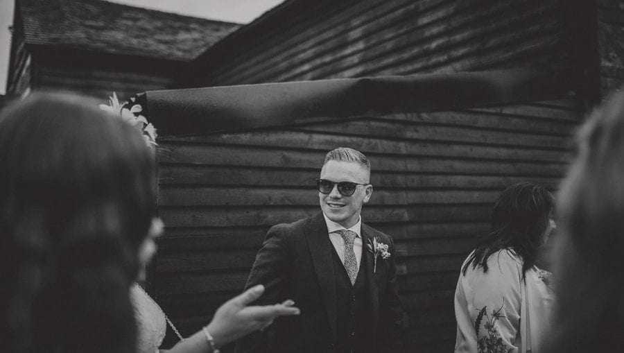 The groom greets friends and family in the courtyard at Over Barn