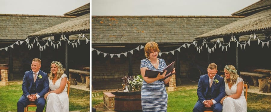 The bride and groom sit in chairs next to each other and listen to a lady speaking during the wedding ceremony