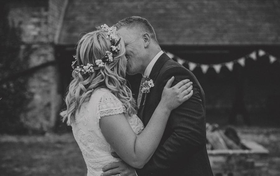 The bride and groom kiss each other at the end of the outdoor wedding ceremony