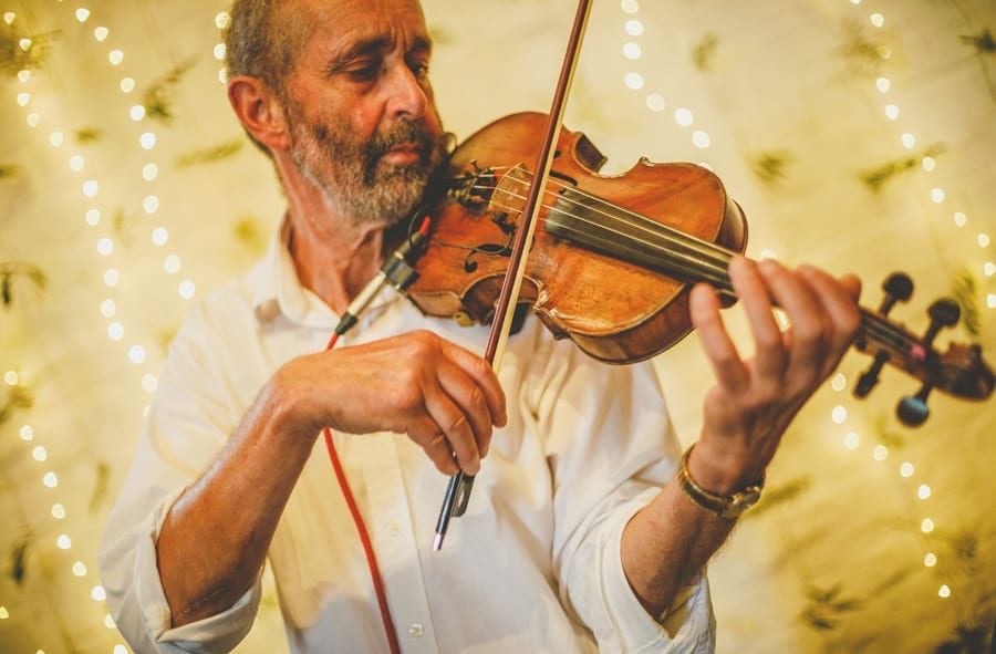 A man plays a violin in the barn