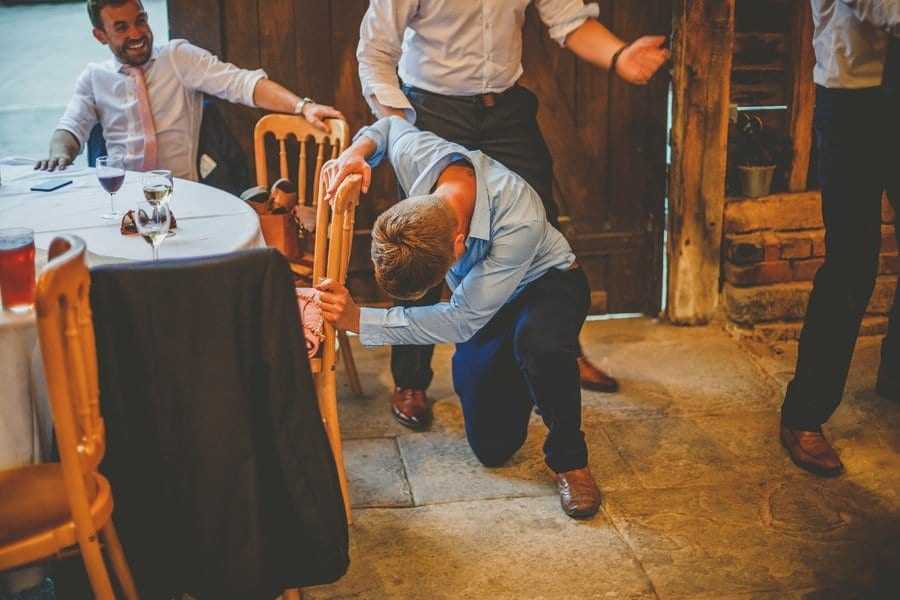 A wedding guest falls onto the floor and attempts to get up in the barn