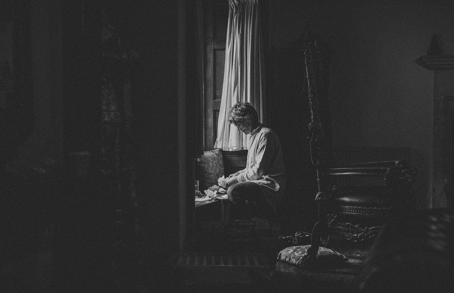 A wedding guest wraps a present next to a window in the cottage