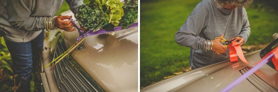 Wedding guests decorating the wedding car with flowers and ribbons