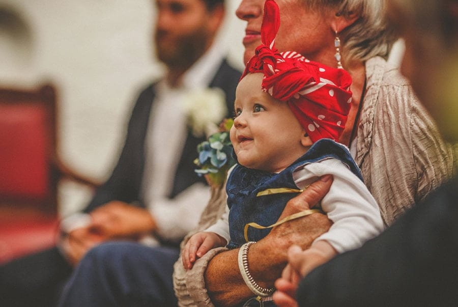 The bride and grooms baby girl smile during the wedding ceremony