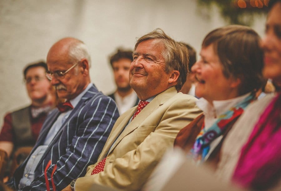 A wedding guest smiles as he sits with friends and family during the wedding ceremony