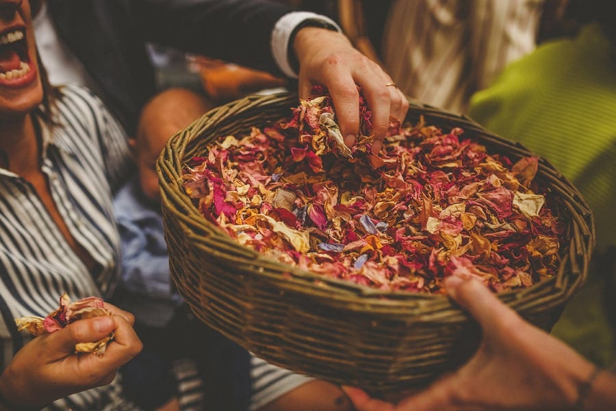 A man picks up confetti from a large wicker bowl