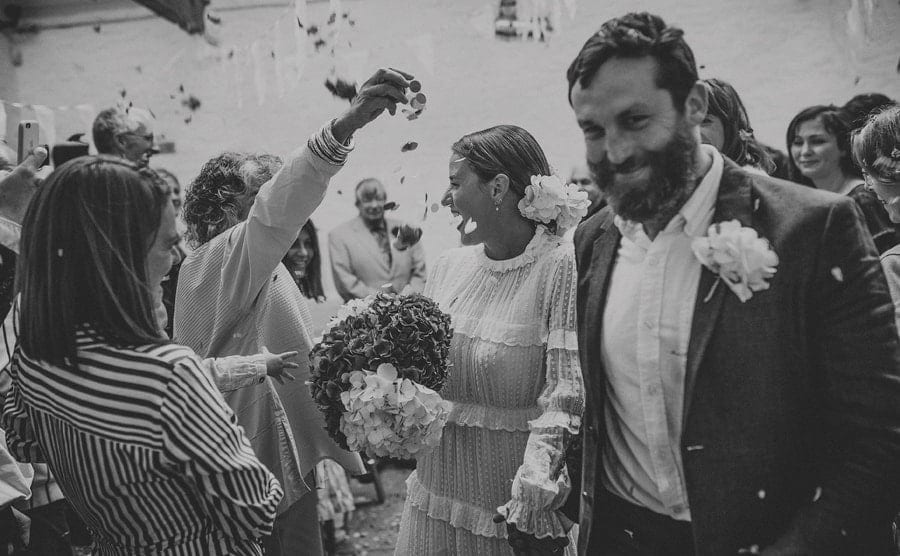 Wedding guests throw confetti over the bride and groom