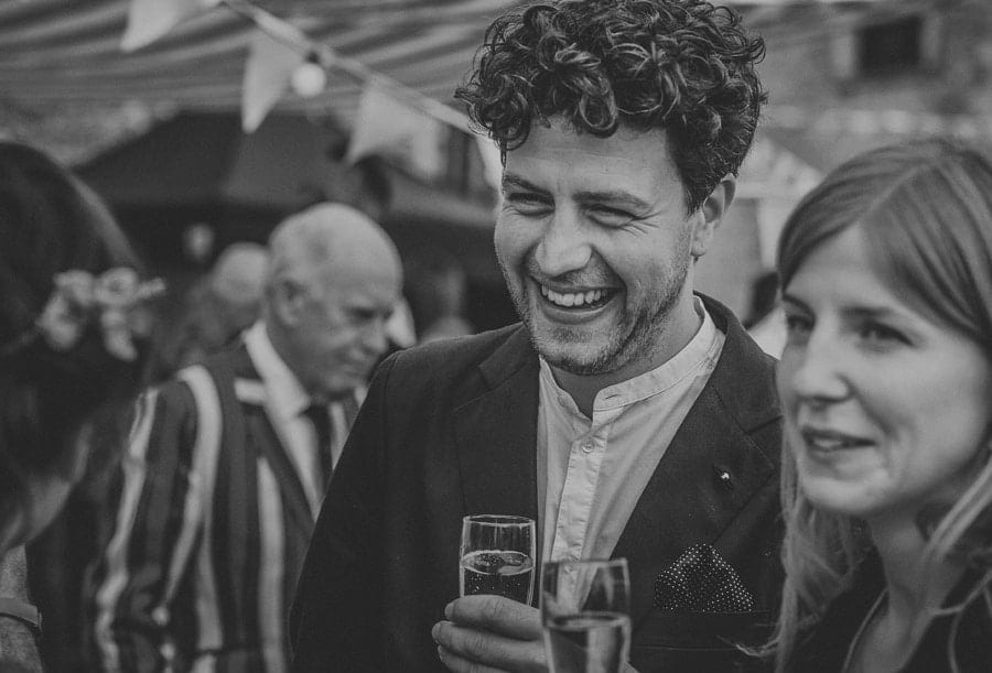 A wedding guest smiles as he chats with friends