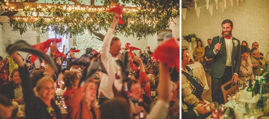 The groom stands up and speaks into a large microphone and the wedding guests congratulate him