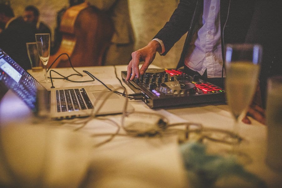 The wedding DJ turns a dial on his mixing desk
