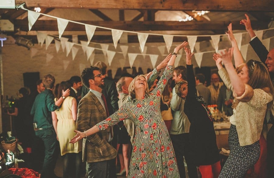 Wedding guests hold their arms up in the air on the dancefloor