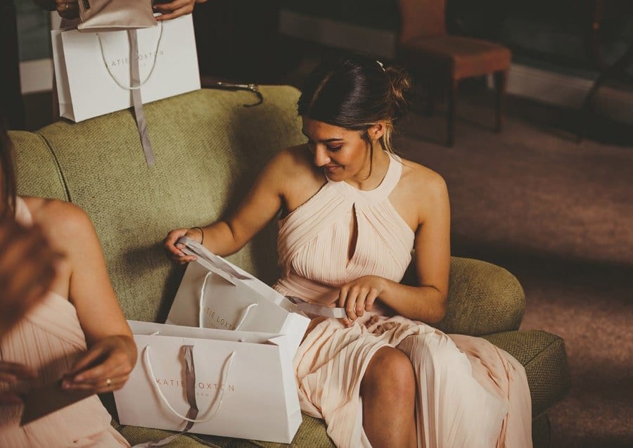 A bridesmaid opens her bag of presents in the Master bedroom