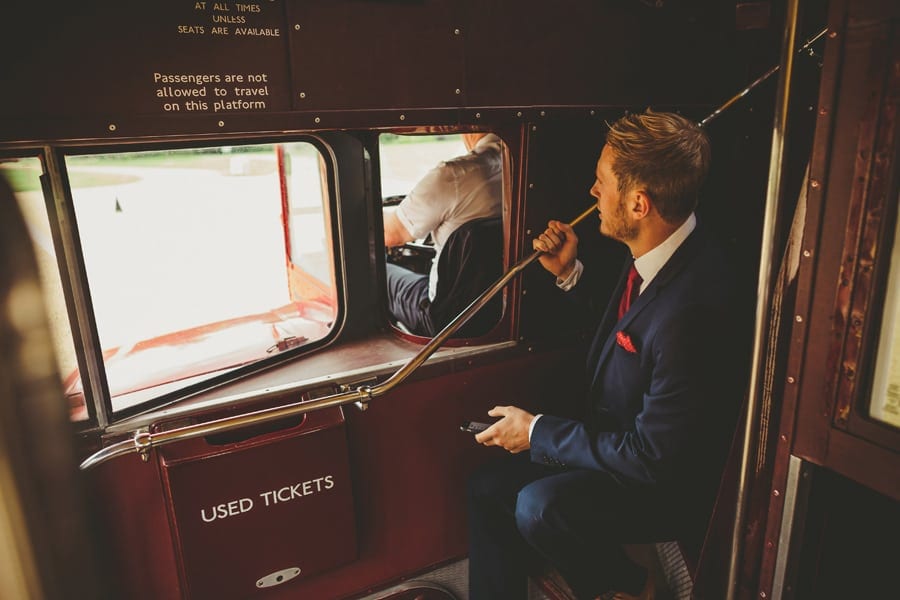 An usher sits on the stairs of the wedding bus on the journey to the church