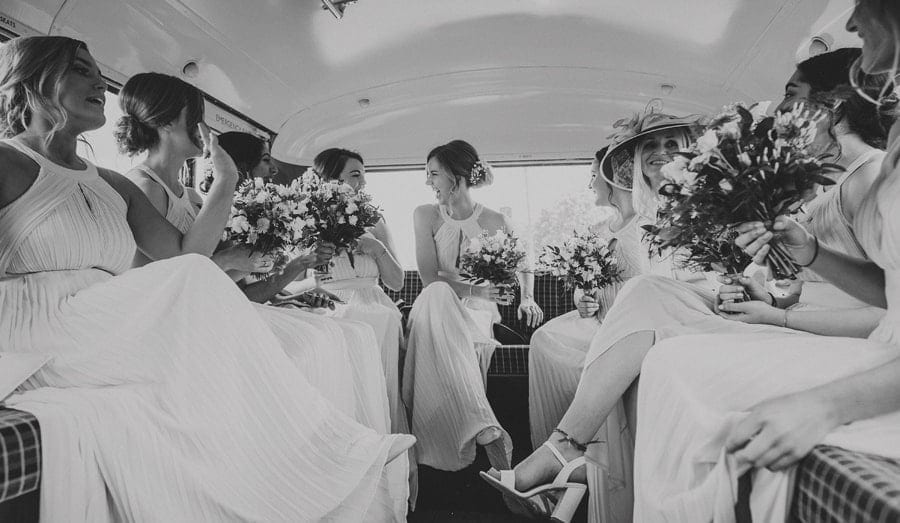 Bridesmaids sit on the back of the wedding bus and share a joke with each other