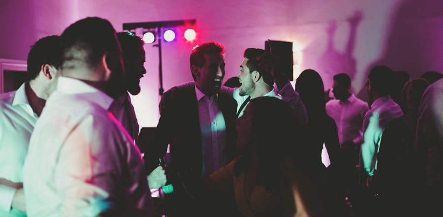 Wedding guests share a joke with each other on the dancefloor