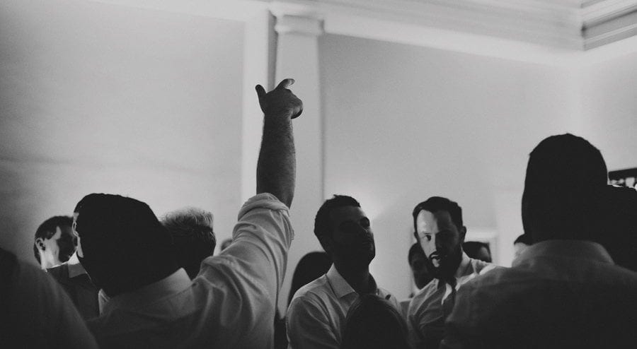 A wedding guest holds his arm up in the air