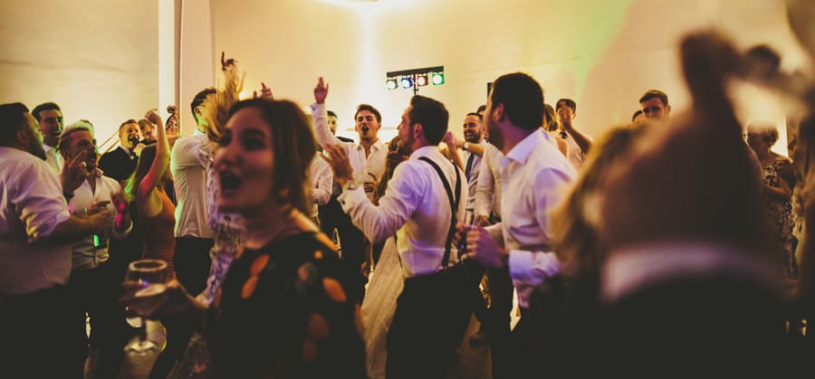Wedding guests on the dancefloor gather together and sing songs