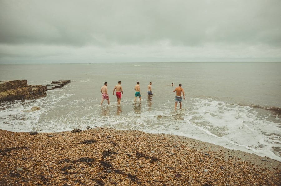The groom and his ushers walk into the sea at Lyme Regis in Dorset