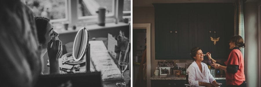 The brides mother sits next to the window in her home and has make up applied to her face