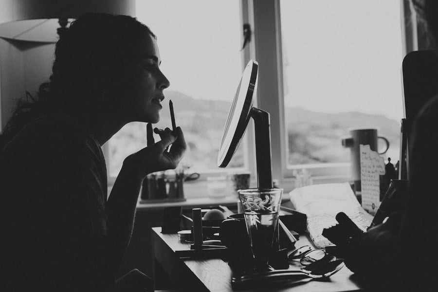 The brides sister applies lipstick to her lips