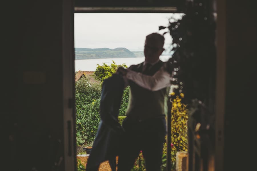 The bride's father puts on his jacket outside his house in Lyme Regis