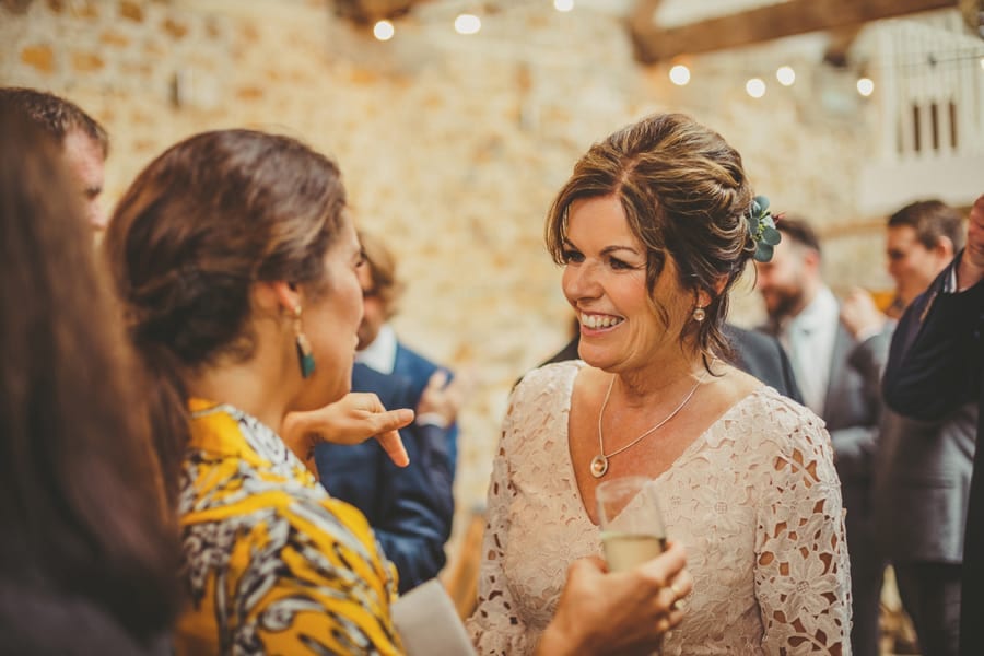 The brides mother smiles and chats with wedding guests