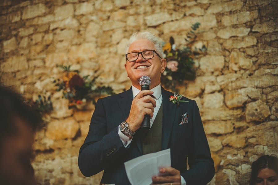 The bride's father closes his eyes and laughs during his speech