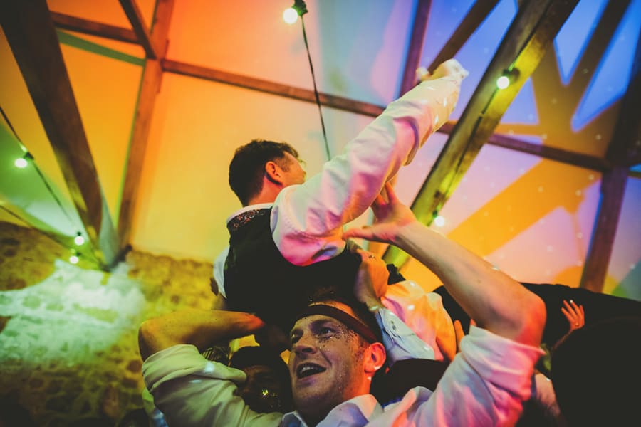 Wedding guests lift the groom in the air on the dancefloor