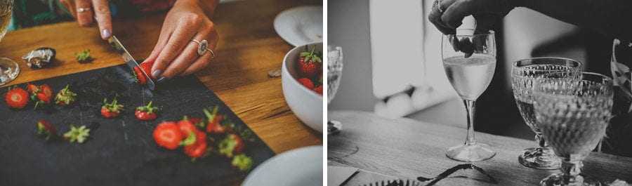 A lady chops up strawberries on a large grey slate and places them into the champagne