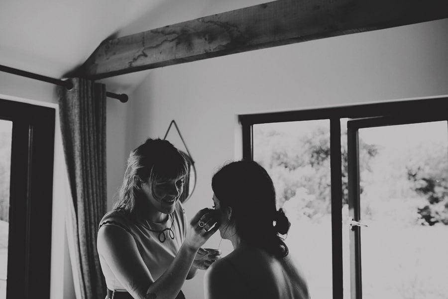 The makeup artist applies mascara to the brides face in the cottage at Yurt retreat in Crewkerne, Somerset