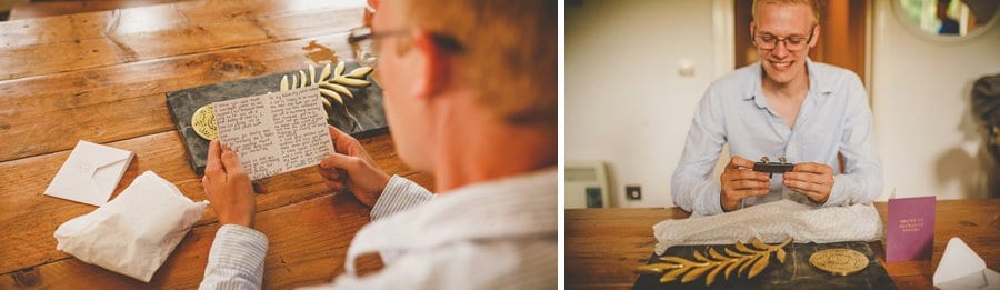 The groom sits at a large wooden table in the cottage and reads a letter written by the bride