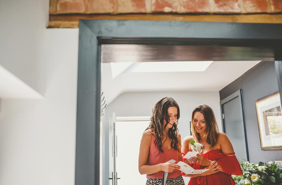 The bride and a bridesmaid read a letter written by the groom in the hallway of the cottage