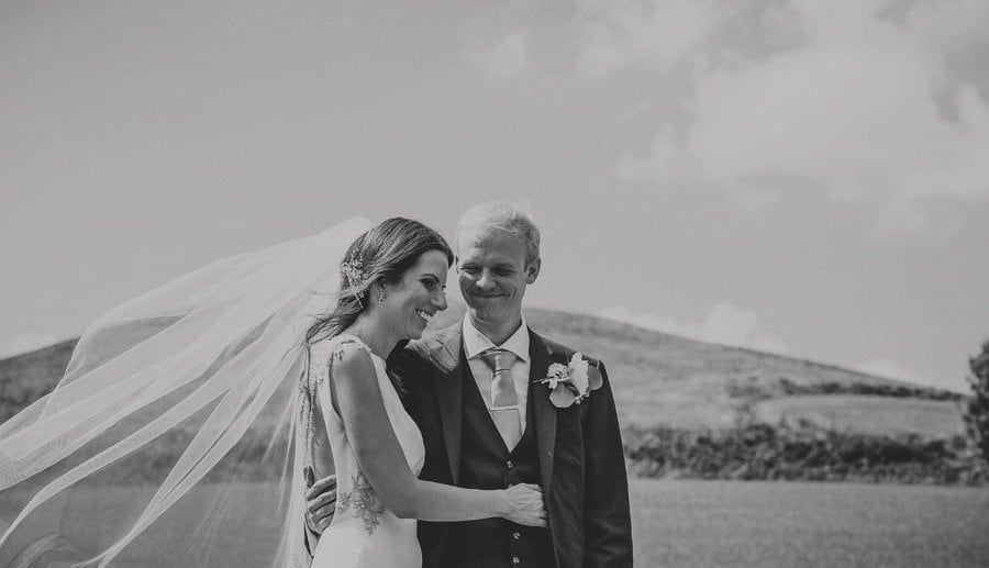 The groom smiles at the bride and puts his arm around her during the wedding ceremony