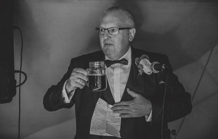 The bride's father holds a drink in his hands and starts his wedding speech in the tipi at yurt retreat