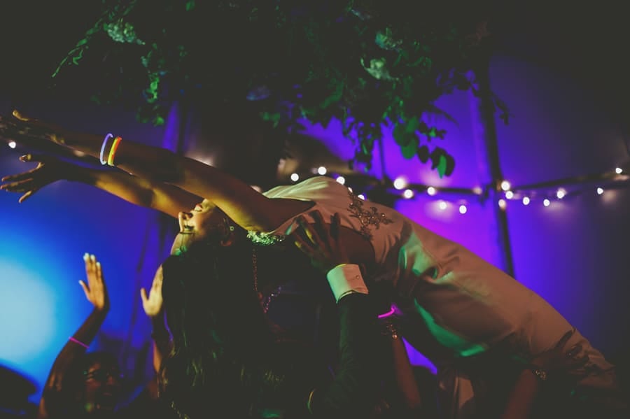 Wedding guests raise the bride in the air on the dancefloor in the tipi