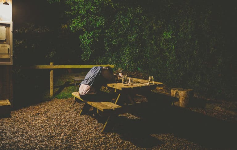 A man lies asleep on a wooden bench outside the tipi at yurt retreat in Crewkerne