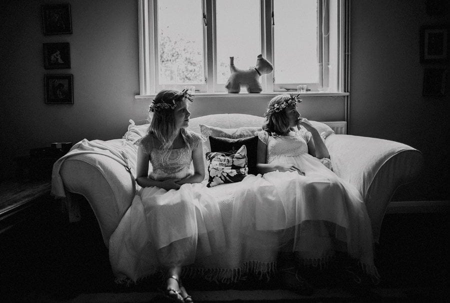 Two flower girls sit on a sofa