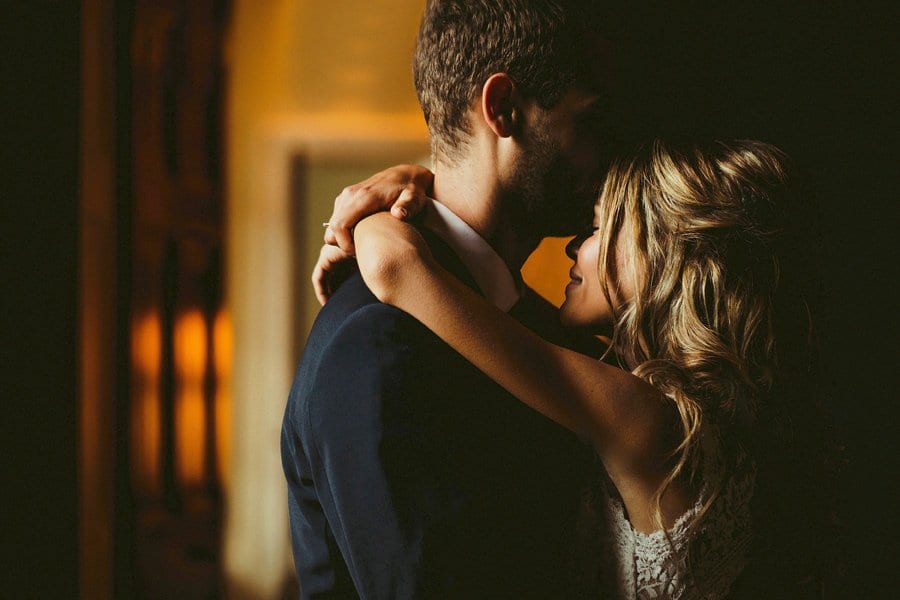 The groom kisses the bride on the forehead as she wraps her arms around his shoulders