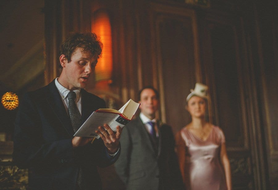 A wedding guest stands in front of the bride and groom and reads a poem during the wedding ceremony at Cowley Manor Hotel in Cheltenham