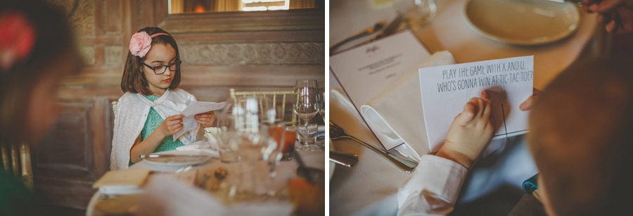 A flower girl reads the menu as she sits at the wedding table