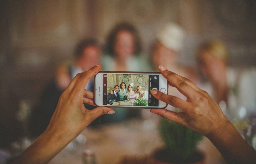 A wedding guest takes a photograph of the bride and groom on a mobile phone