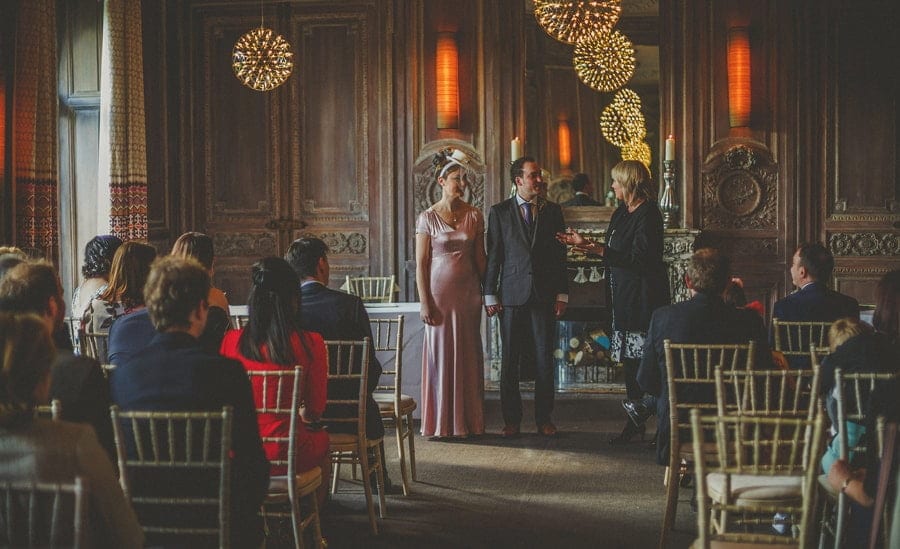 The bride and groom stand next to each other and listen to the registrar during the wedding ceremony at Cowley Manor Hotel