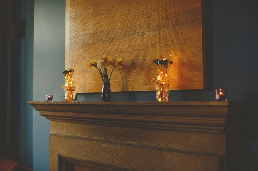 A vase with flowers inside it on a fireplace at Cowley Manor