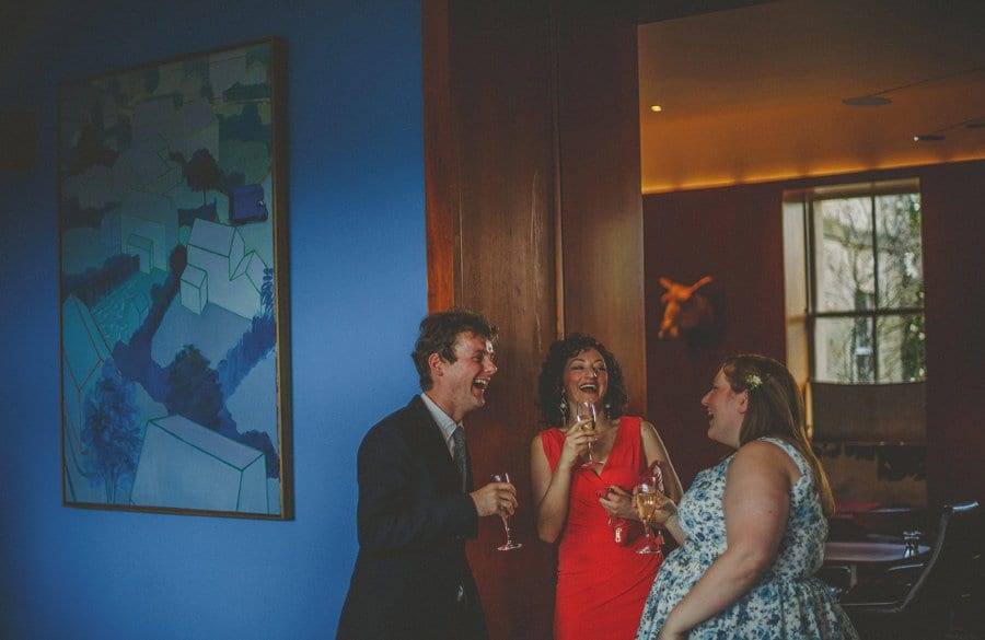 Wedding guests drinking champagne chat amongst themselves at Cowley Manor