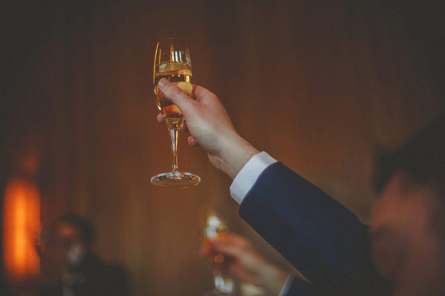A flute of champagne is raised in the air by the groom