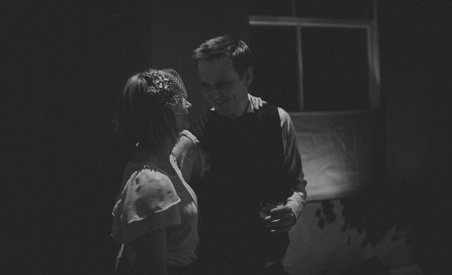 A man and his wife stand next to each other and chat on the dancefloor at Cowley Manor