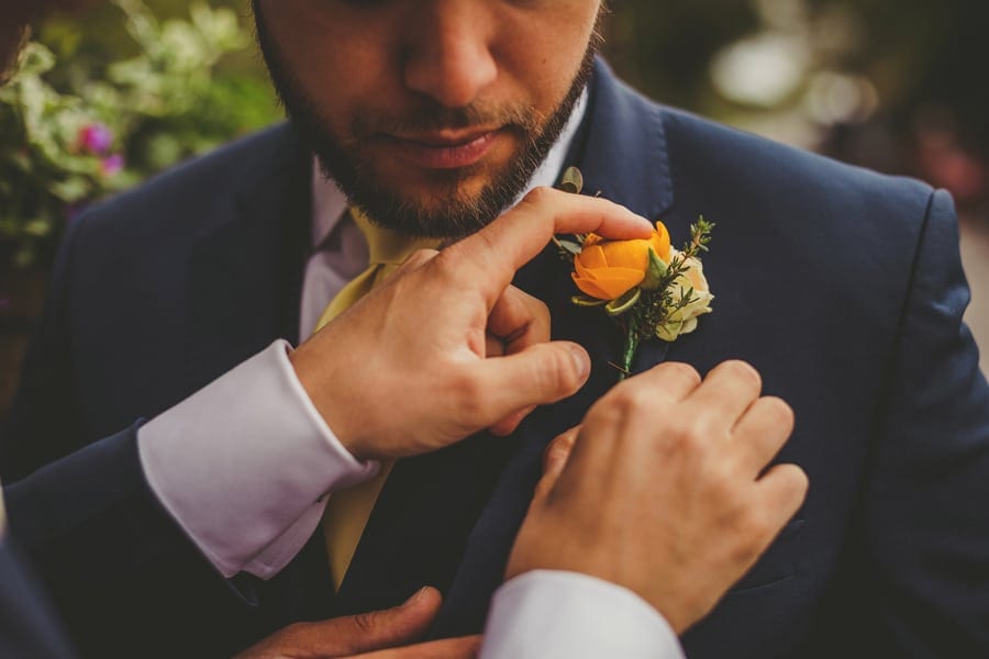 The groom fastens a flower to an ushers suit jacket