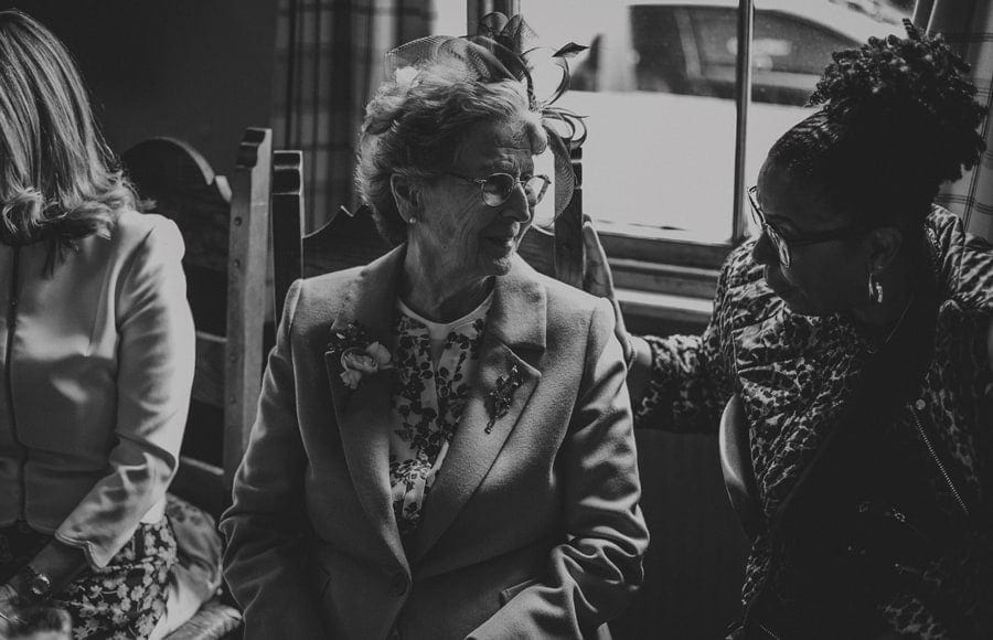 The grooms grandmother sits in a public house and listens to her friend talk