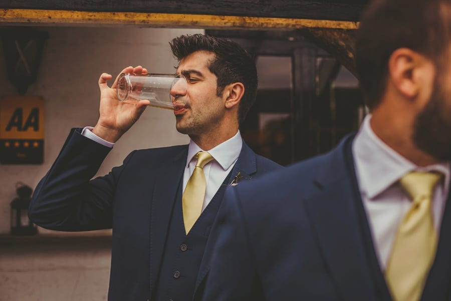 An usher finishes drinking his pint of beer outside a public house in East Hampshire