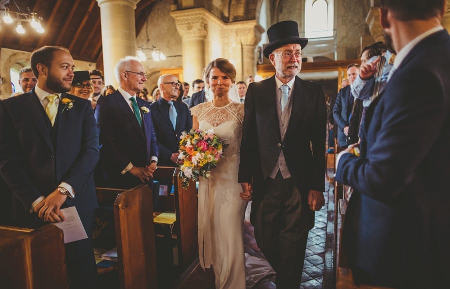 The bride and her father walk down the aisle of the church and are greeted by friends and family